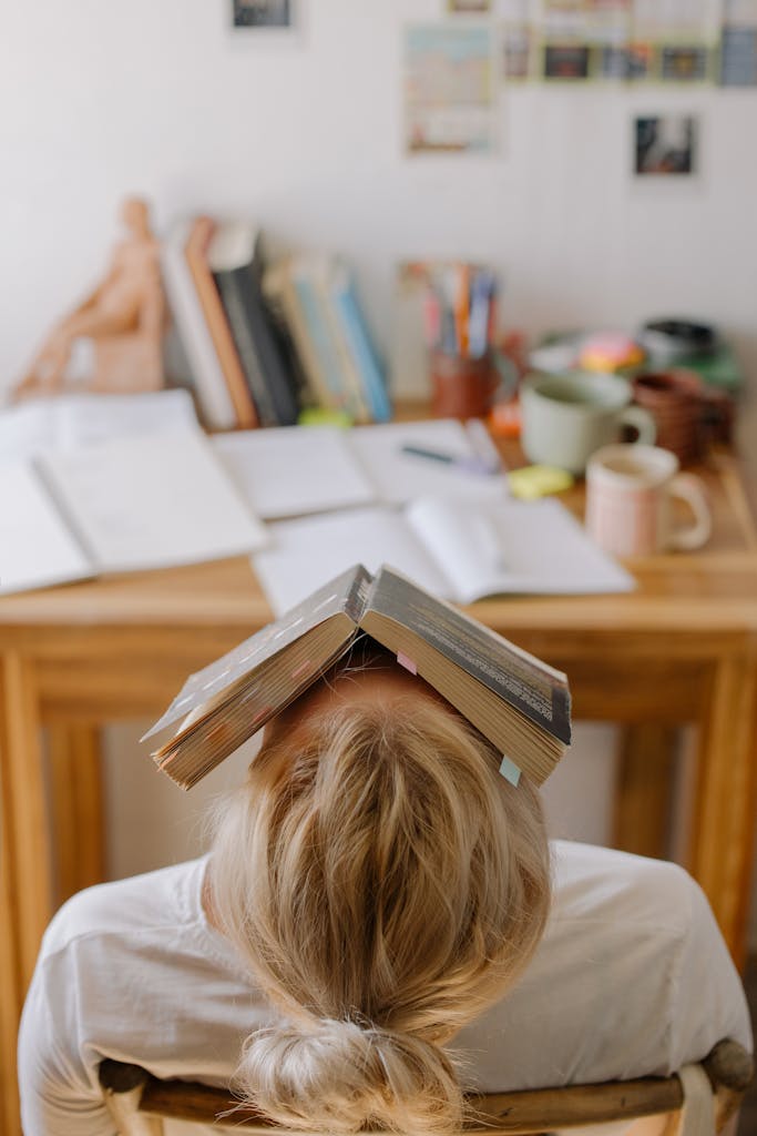 journaling for burnout: overwhelmed tilting backward in chair with a book laying on her face 