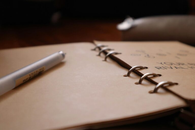 Close-up of an open notebook with a pen lying on a wooden desk, inviting creativity.